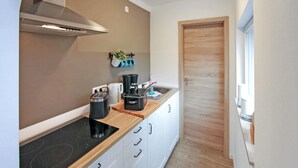 Une cuisine compacte équipée d’une cuisinière, d’une machine à café et d’une bouilloire sur le plan de travail.