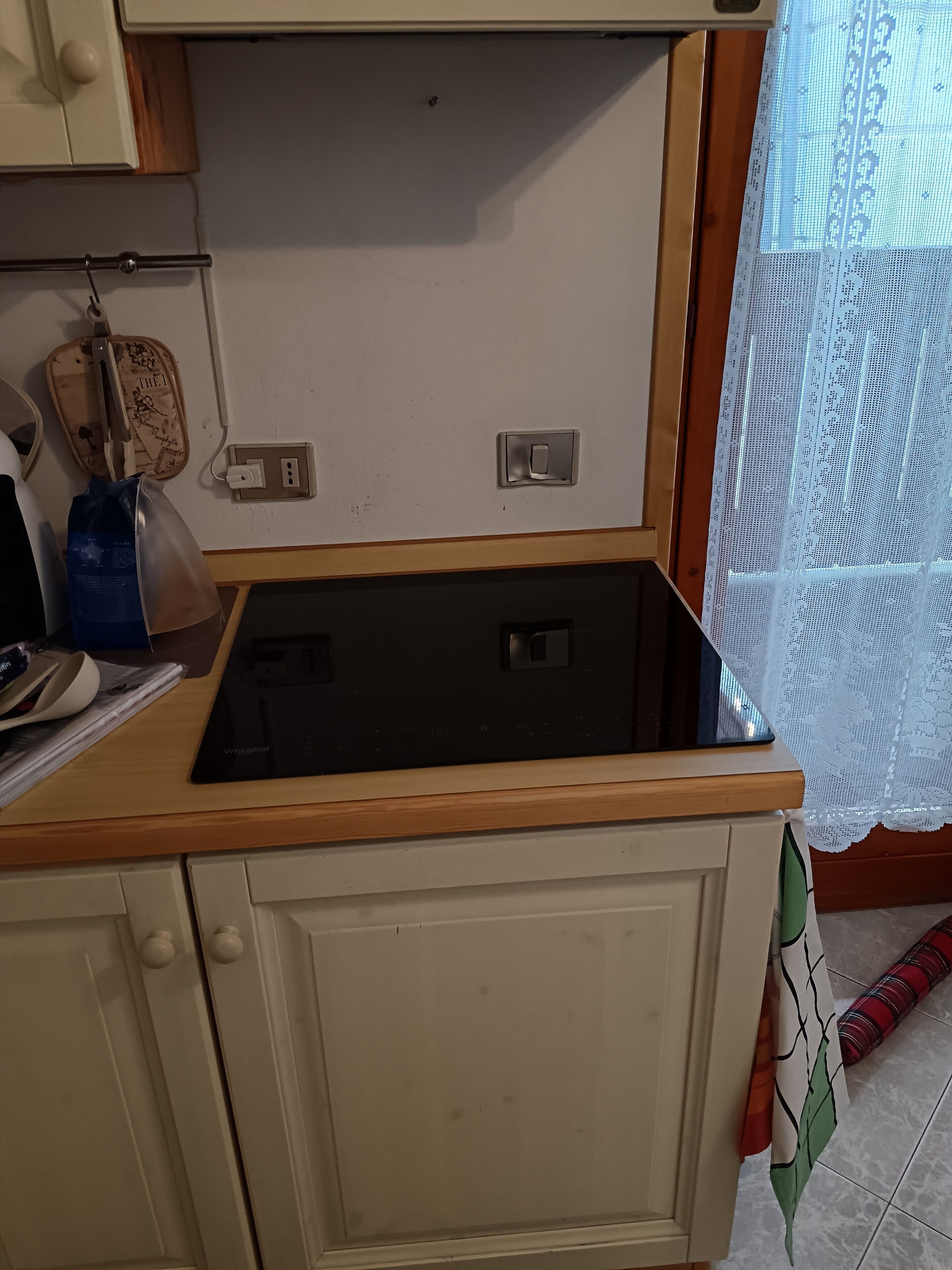 A kitchen with a black stove, a wooden countertop, and a white cabinet.