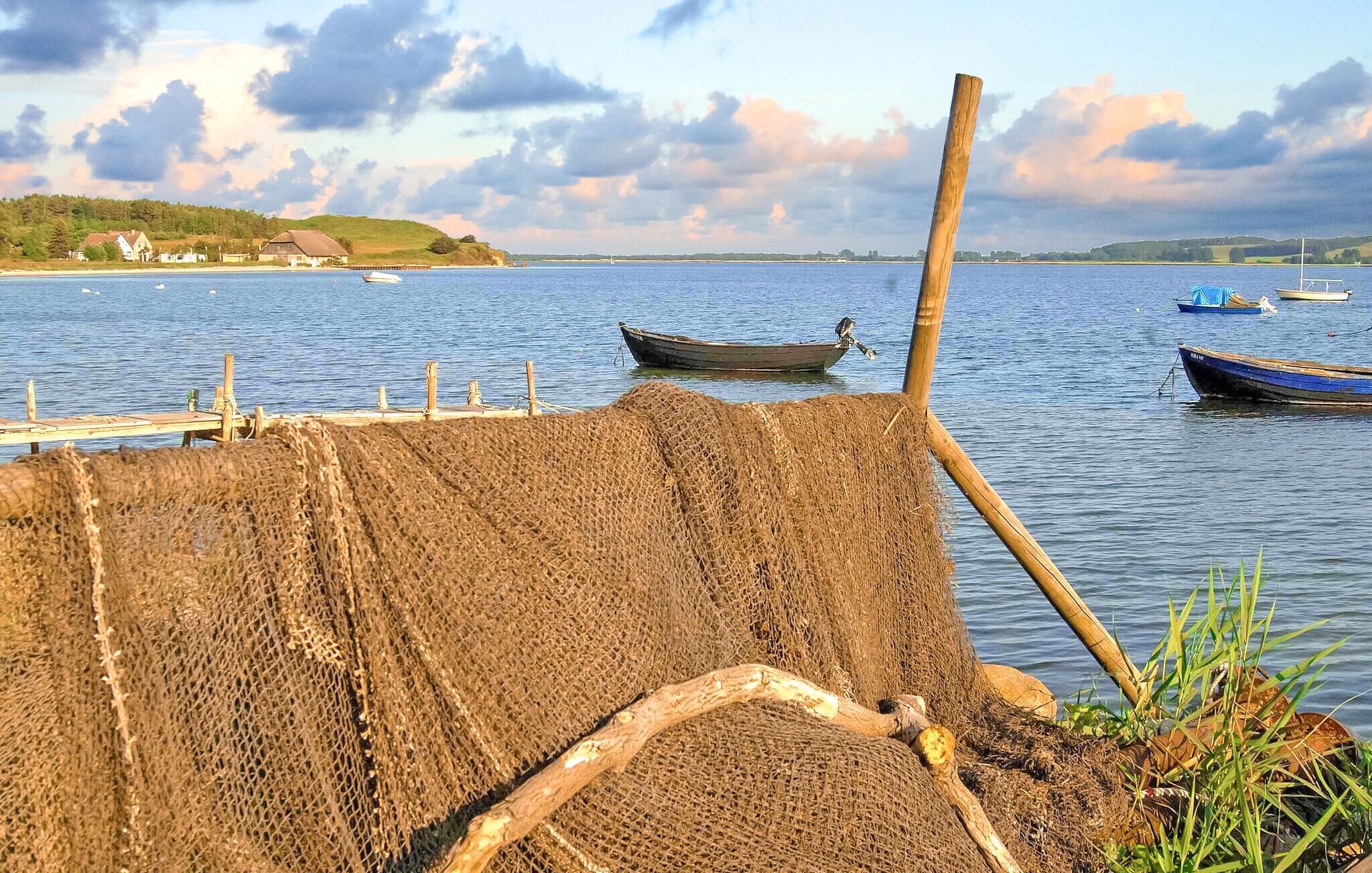 A calm lake with boats, a dock, and a grassy area with a wooden post.
