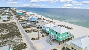 Une zone côtière comprenant des propriétés en bord de mer, notamment des maisons et une route menant à la plage.