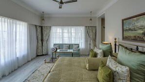 Un dormitorio con cama, sofá, ventilador de techo y un cuadro en la pared.