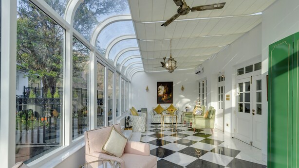Una habitación amplia con ventanas grandes, piso a cuadros y una puerta verde.