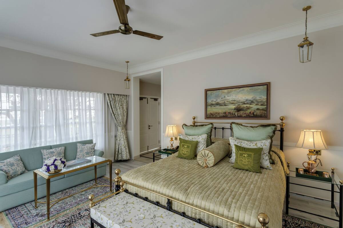 A bedroom with a bed, a sofa, a coffee table, and a painting on the wall.