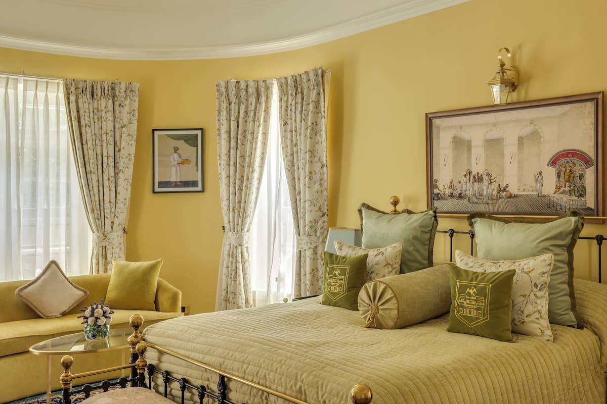 A room with a bed, a sofa, a painting, and curtains.