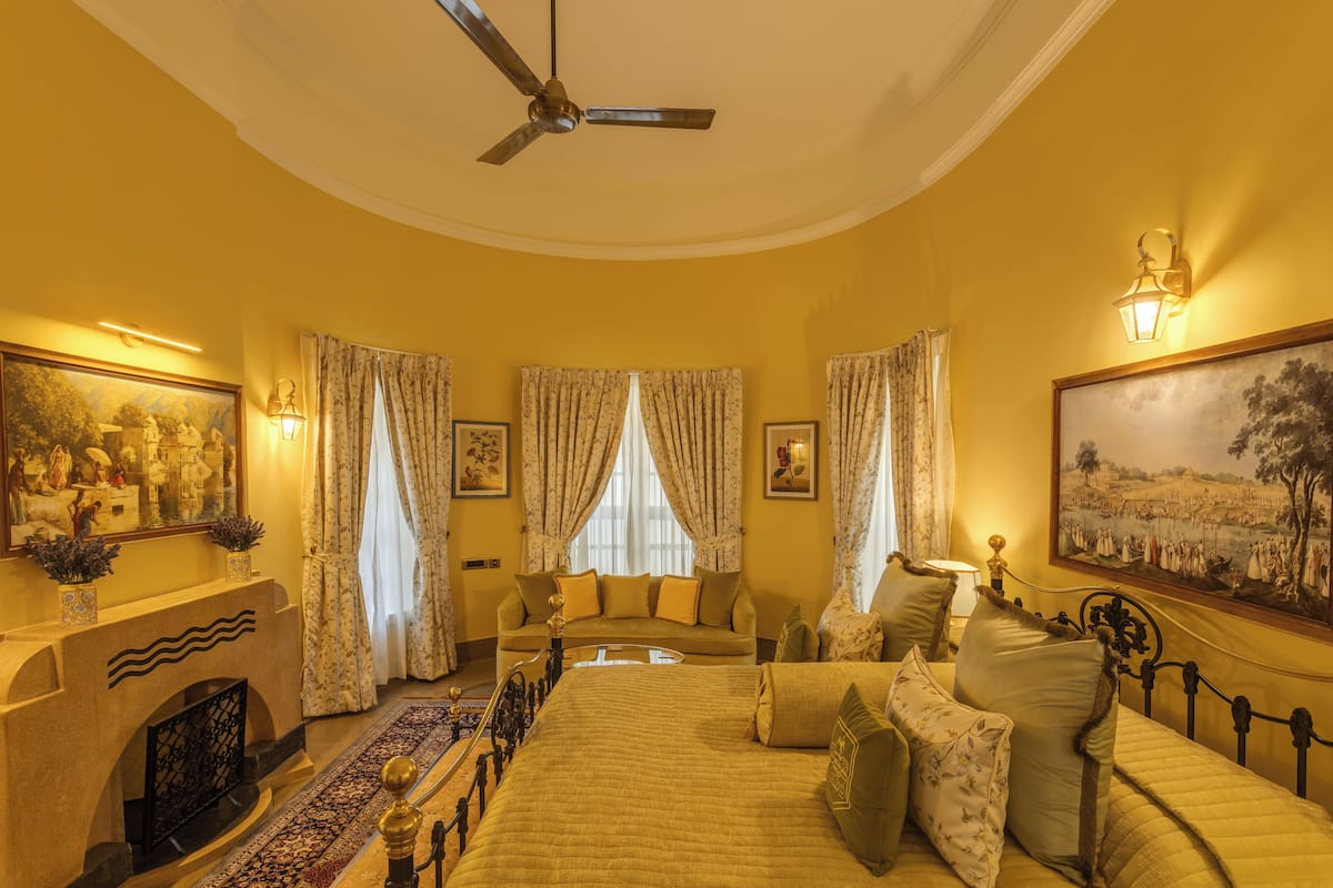 A room with a bed, a sofa, a fireplace, and a ceiling fan.