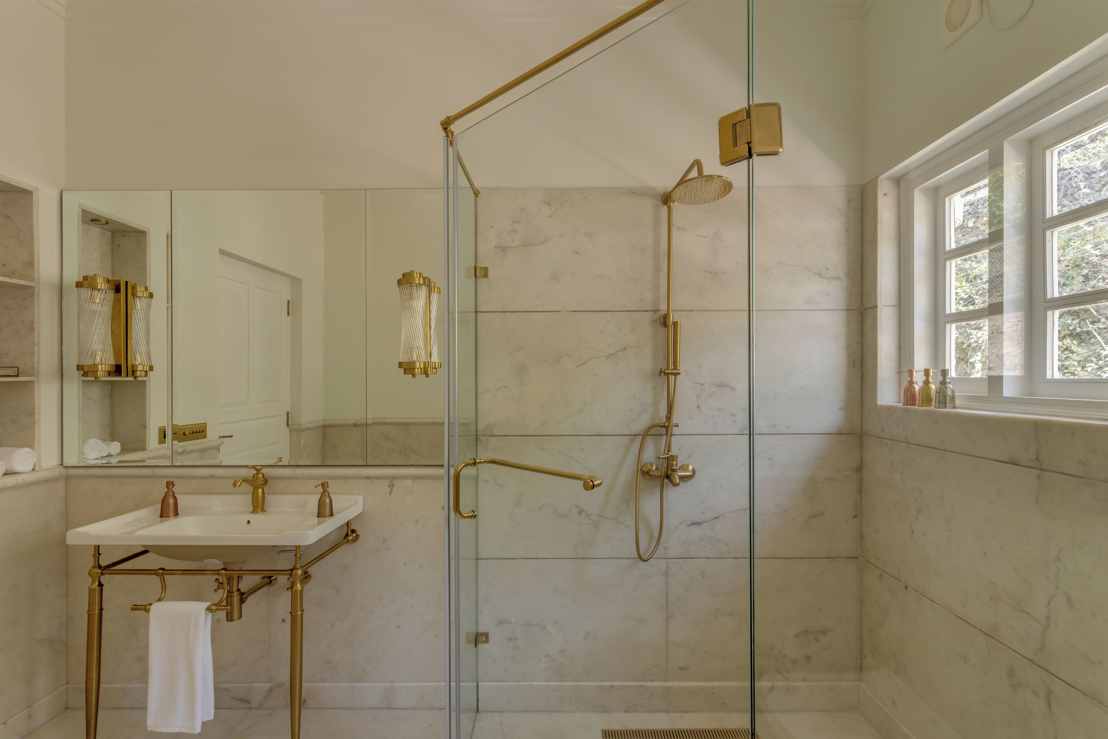 Une salle de bain avec une douche à parois de verre, un meuble-lavabo avec un évier blanc et un grand miroir.