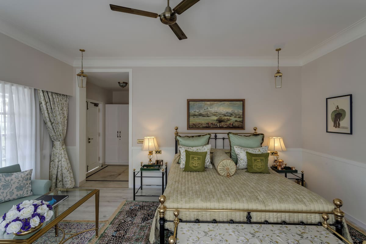 A bedroom with a bed, bedside tables, a ceiling fan, and a painting on the wall.