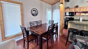 A dining area with a wooden table and chairs, a kitchen with wooden cabinets, and a wall with a circular design.