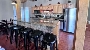 A modern kitchen with wooden cabinets, a granite island, and black bar stools.