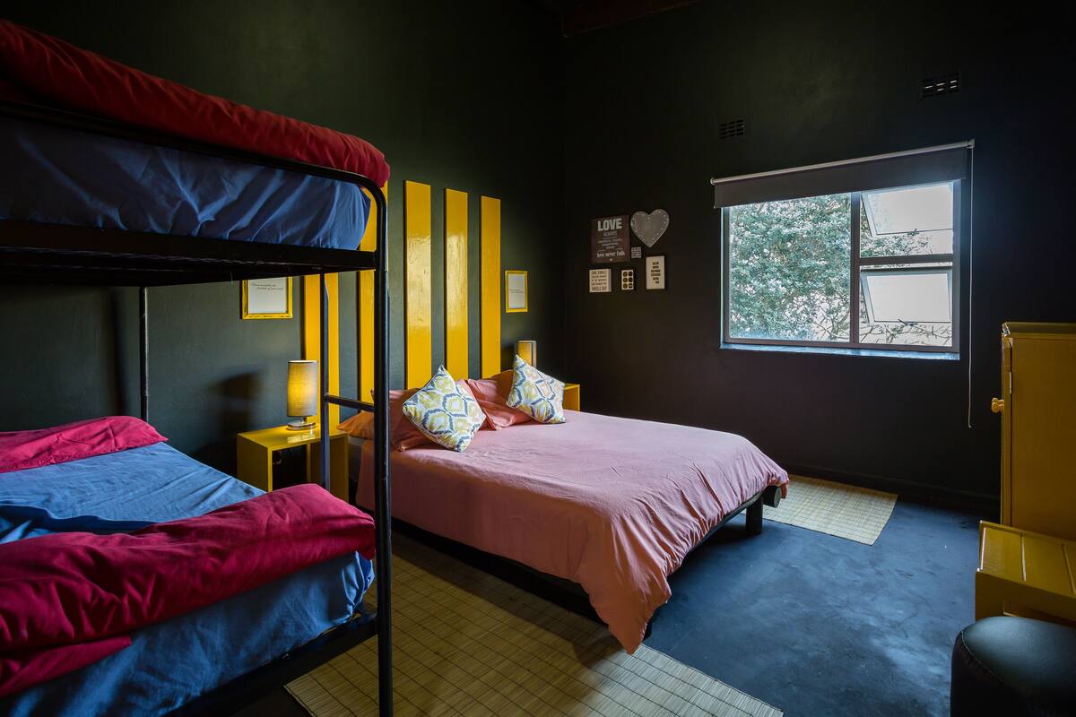Ein Zimmer mit Etagenbetten, einem Nachttisch mit Lampe, einem Fenster mit Aussicht und einer Wand mit Herz-Dekoration.