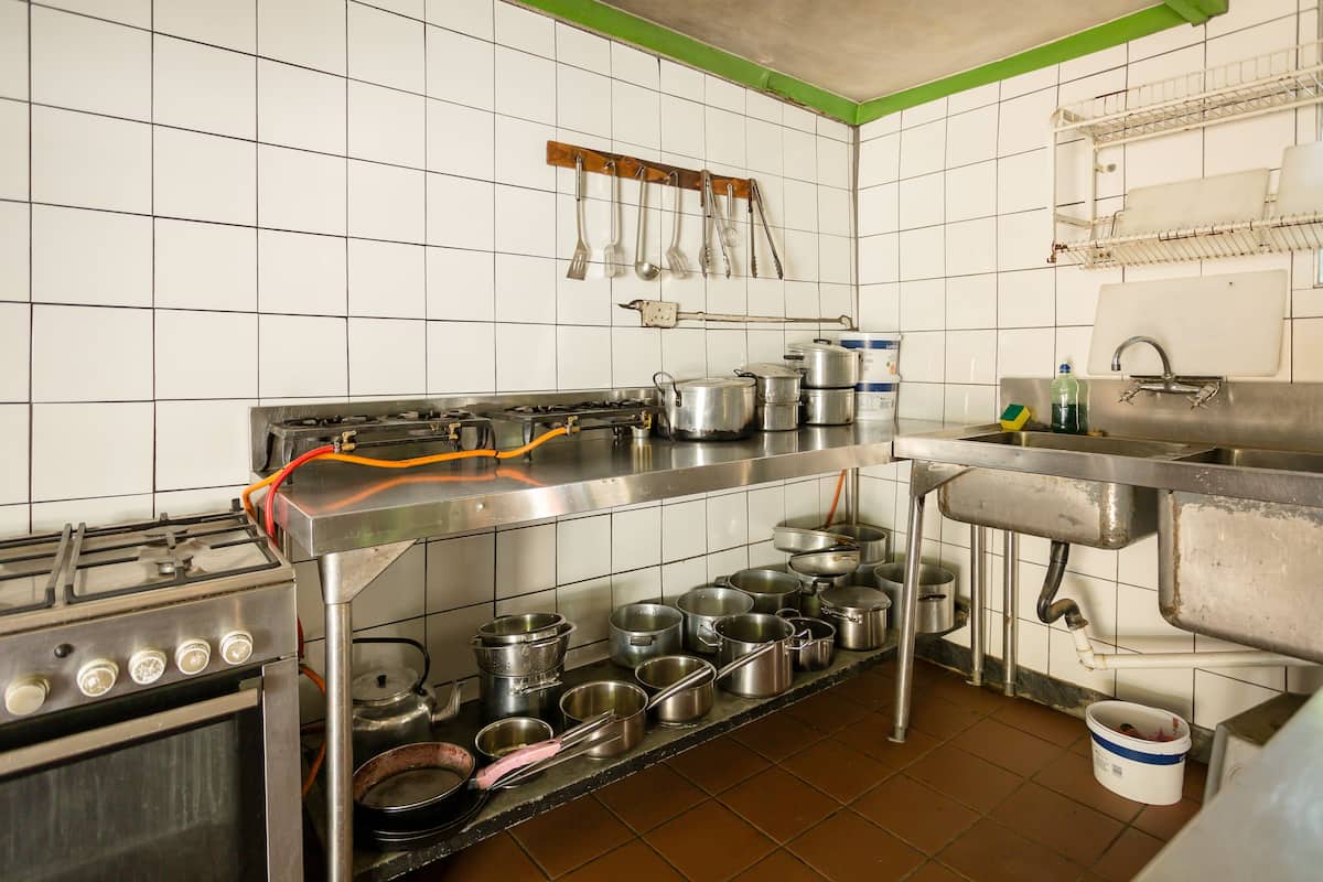 Eine Küche mit Edelstahlgeräten, Töpfen, Pfannen und Küchenutensilien in Regalen.