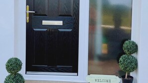 A dark wooden front door with a glass panel and a welcome sign. - Serenity Holiday Let in South Chard (Chard)