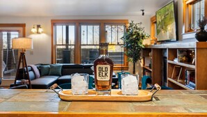 Una botella de whisky Old Elk sobre una bandeja de madera con dos vasos de whisky.