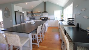 A spacious kitchen with a central island, white cabinetry, and a modern stove. - Beautiful Great Island Ocean Club Home (2368) (Yarmouth)