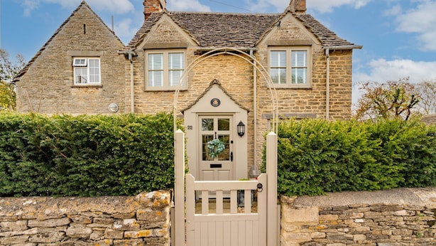 A stone house with a traditional design, featuring a central door with a wreath, a stone wall, and a well-maintained hedge. - Gable Cottage  - Dog Friendly, Meysey Hampton near Cirencester (Meysey Hampton)