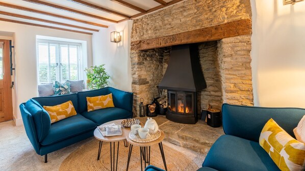 A cozy living room with a stone fireplace, blue sofas, and a small coffee table.