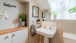 A bathroom with a star decoration, a framed sign, a mirror, a sink, and a potted plant.