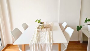 A white dining table with a woven placemat, a potted plant, and a glass jar. - Cozy Aparment with Balcony, Hammock & Washing Machine (Buenos Aires)