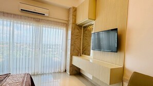Ett modernt hotellrum med en stor säng, en soffa, en TV som är monterad på väggen och en kristallkrona.