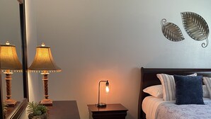 A bedroom with a bed, a nightstand with a lamp, a dresser, and a mirror. - Lovely and Cozy 1 bedroom apartment  (Pearland)
