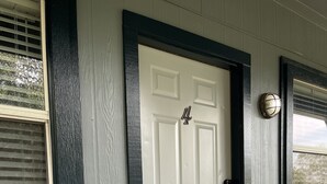 A white door with a black frame, a small number '4' above it, and a doormat on the porch. - Lovely and Cozy 1 bedroom apartment  (Pearland)