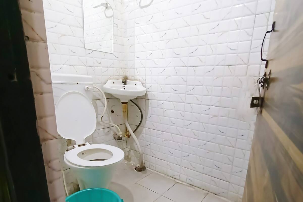 Pieni kylpyhuone, jossa on wc, pesuallas ja sininen ämpäri.