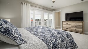 A bedroom with a bed, a TV, a ceiling fan, and a view of a balcony. - New to the Vacation Market! Unit 2B Canal Place (Lewes)