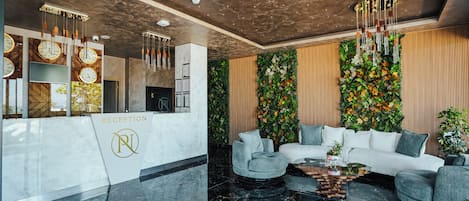A reception area with a marble floor, a reception desk, a white sofa, and a wall with vertical gardens.