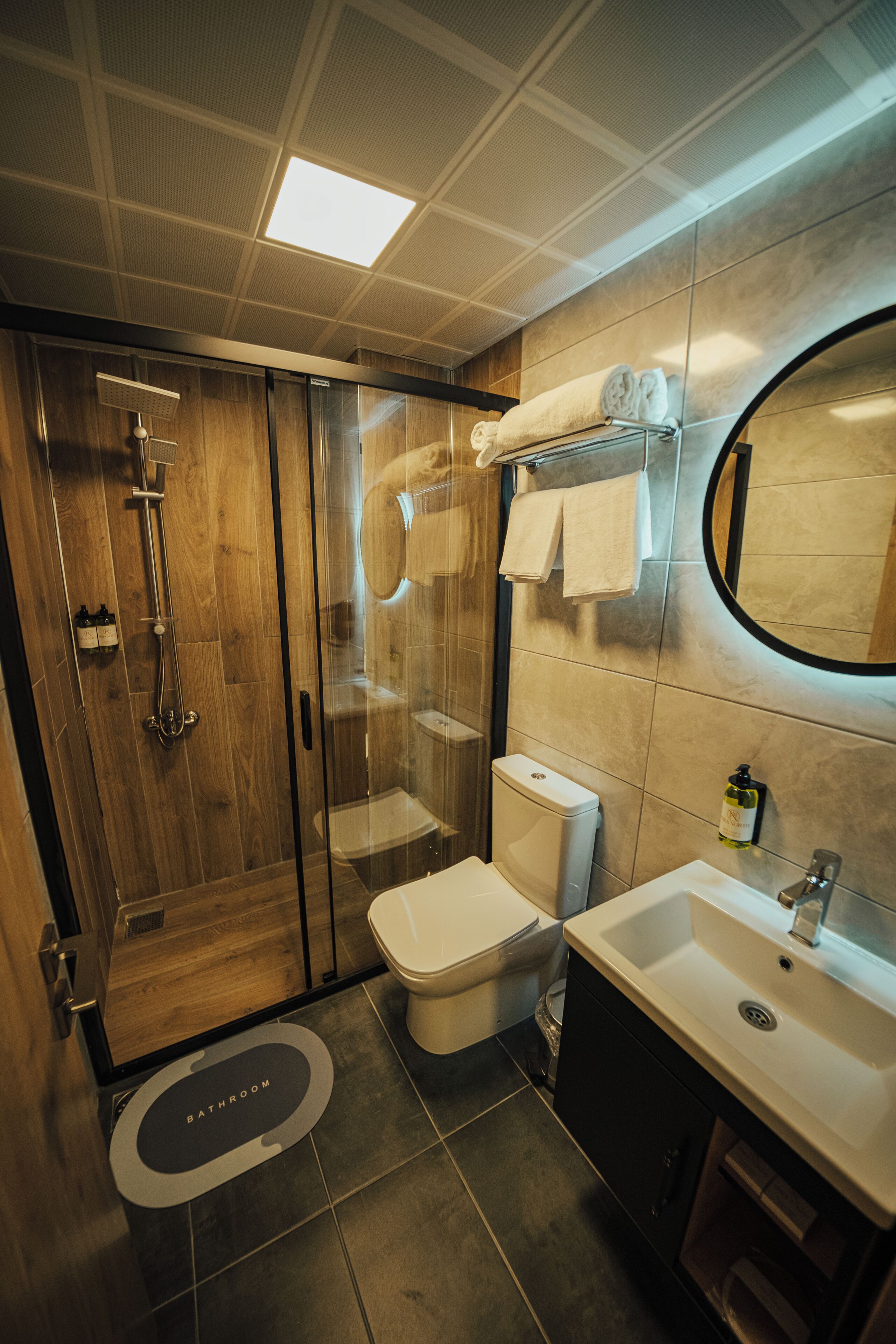 A modern bathroom with a glass-enclosed shower, a toilet, and a sink.