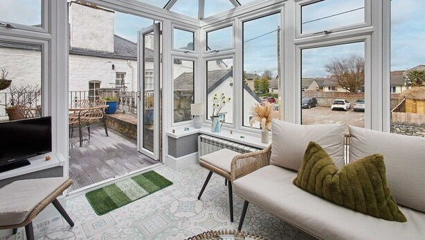 A conservatory with a TV, sofa, and wicker furniture.