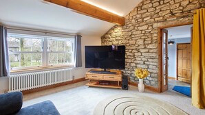 A living room with a stone wall, a large TV, a sofa, and a spiral rug.