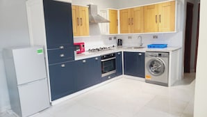 Une cuisine compacte équipée d’un réfrigérateur, d’un four à micro-ondes, d’une cuisinière, d’un four et d’un lave-linge.