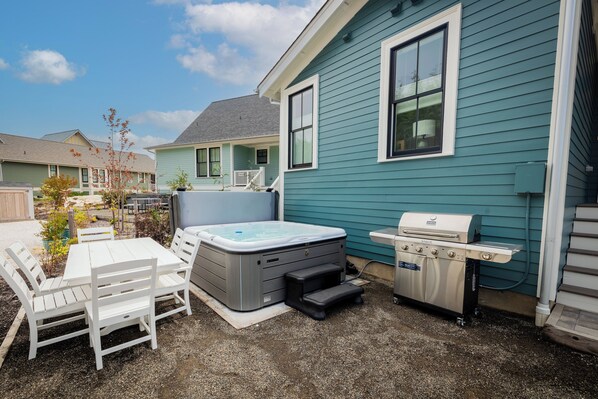 Ein Garten mit Whirlpool, Grill und Sitzgelegenheit im Freien.