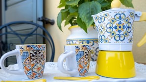 Een dienblad met twee bekers met dessin en een koffiepot, geel en wit.