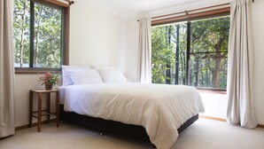 A bedroom with a bed, a nightstand, and a window with curtains. - Woodbine Homestead a Bush and Beach Retreat with a comfortable cosy feel (Hallidays Point)