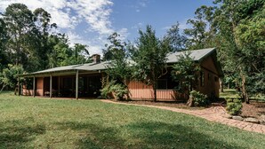 A two-story house with a covered porch and a brick pathway leading to the entrance. - Woodbine Homestead a Bush and Beach Retreat with a comfortable cosy feel (Hallidays Point)