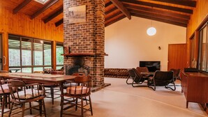 A spacious living room with a large brick fireplace, wooden furniture, and a television. - Woodbine Homestead a Bush and Beach Retreat with a comfortable cosy feel (Hallidays Point)