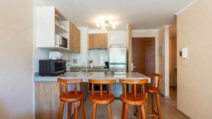 A modern kitchen with a central island, wooden bar stools, and built-in appliances.