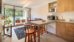 A modern kitchen with a central island, wooden cabinets, and a dining area with bar stools.