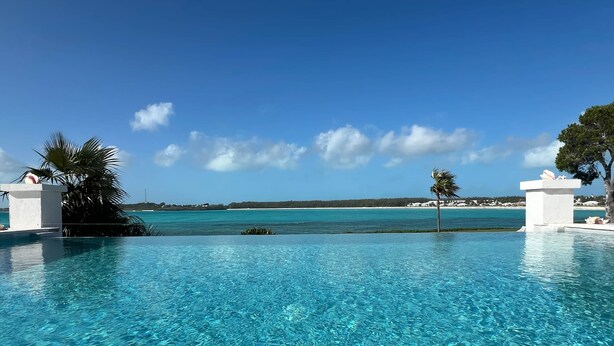 A clear blue pool with a view of the ocean and a distant shoreline. - Vantage Point Exuma Ultra-Luxury Villa - Heated Pool & Golf Cart (Rokers Point Settlement)