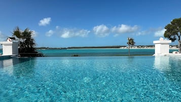 Une piscine d’un bleu éclatant, avec vue sur l’océan et une côte lointaine.