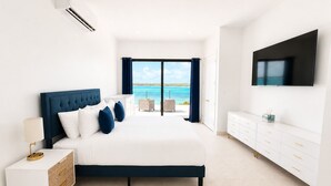 Ein Schlafzimmer mit Bett, Nachttisch, Fernseher und Meerblick.