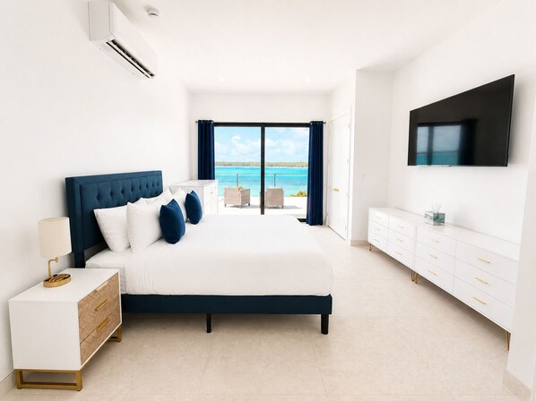 A bedroom with a bed, bedside table, TV, and a view of the sea. - Vantage Point Exuma Ultra-Luxury Villa - Heated Pool & Golf Cart (Rokers Point Settlement)