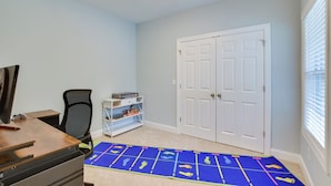 A room with a desk, chair, and a blue mat with footprints. There is a white door and a window with blinds.