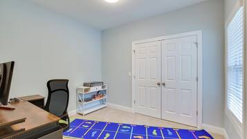A room with a desk, chair, and a blue mat with footprints. There is a white door and a window with blinds.