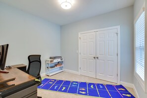 A room with a desk, chair, and a blue mat with footprints. There is a white door and a window with blinds.