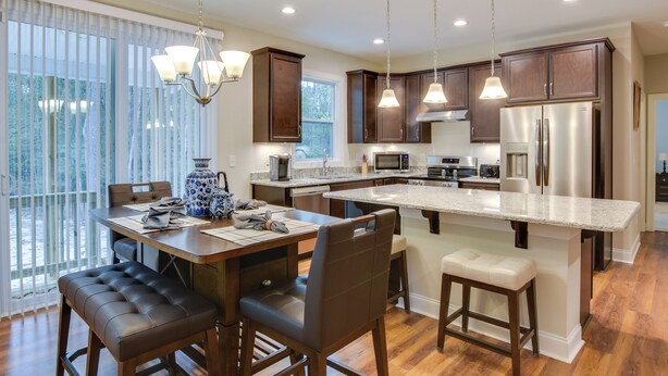 A modern kitchen with dark wooden cabinets, stainless steel appliances, and a central island with bar stools. - West End Home, Close to Pinehurst Golf Courses! (West End)