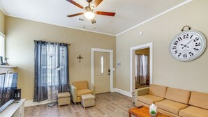 A living room with a sofa, armchair, and ottoman, a wooden coffee table, and a large wall clock. - Cozy Vicksburg Home w/ Patio ~ 1 Mi to Riverfront! (Vicksburg)