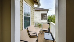 A covered porch with two beige chairs and a small table, overlooking a white house with a visible window and a white railing. - Cozy Vicksburg Home w/ Patio ~ 1 Mi to Riverfront! (Vicksburg)