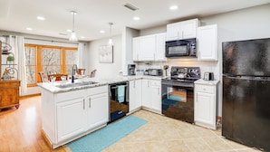 A modern kitchen with white cabinets, a black refrigerator, a microwave, and a stove. - Golf Course Views: Condo in Blue Ridge Mountains! (Burnsville)